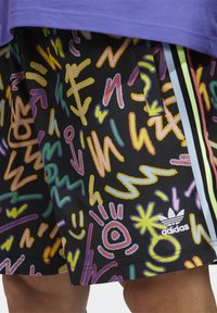 Pantaloncini neri con un motivo astratto colorato di linee ondulate e forme, con logo Adidas bianco e dettagli a strisce in colori pastello.