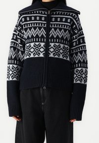 Námořnická a světle šedá pletená svetr na zip s geometrickými vzory, žebrovaným lemem a manžetami, volným střihem a vysokým límcem.