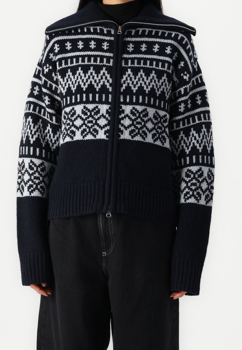 Námořnická a světle šedá pletená svetr na zip s geometrickými vzory, žebrovaným lemem a manžetami, volným střihem a vysokým límcem.
