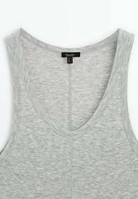 Débardeur gris avec un col en V profond, fait d'un tissu doux et texturé. Présente des coutures surpiquées et une étiquette imprimée à l'intérieur du col.