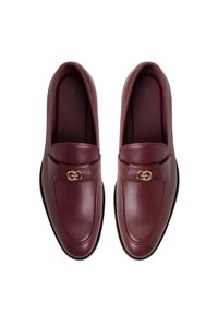 Bordeaux leren loafers met een gladde textuur, voorzien van een decoratieve hardware-accent in goudtint en een klassiek ontwerp.