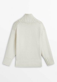 Pull en tricot blanc avec un col montant côtelé, des poignets côtelés et une coupe décontractée, présentant un tissu texturé et un design simple.