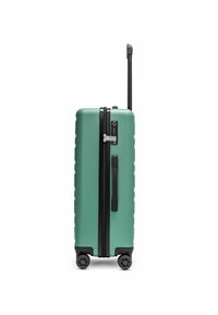 Valigia rigida di colore teal con cerniere e dettagli neri, dotata di manico telescopico e quattro ruote per la mobilità. Design aerodinamico.