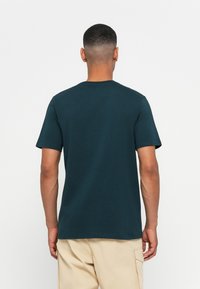 Donker teal katoenen t-shirt met korte mouwen en een ronde hals. Glad textuur en een eenvoudig, ongecompliceerd ontwerp.