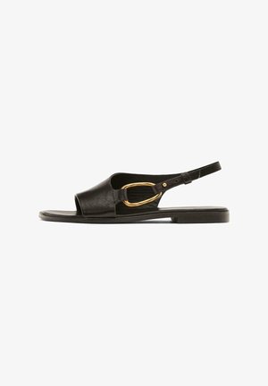 Zwarte leren slingback sandaal met een ronde neus, open design en een goudkleurige ovale gespsluiting aan de zijkant. Platte zool met een minimale textuur.