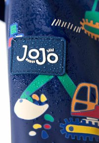 Jūrų mėlynumo vandeniui atsparus audinys su tekstūruota "JoJo" etikete, spalvingais statybinės technikos grafikos vaizdais ir lietaus lašo detalėmis.