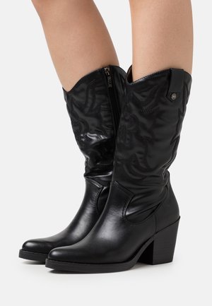 Bottes de cowboy en cuir noir avec un talon légèrement surélevé, ornées de broderies sur la tige et équipées d'une fermeture éclair latérale pour un enfilage facile.