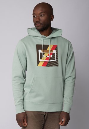 Mintgroene hoodie met een retro cassettebandje grafiek in bruin, rood en geel, voorzien van een voorzak in kangoeroestijl.