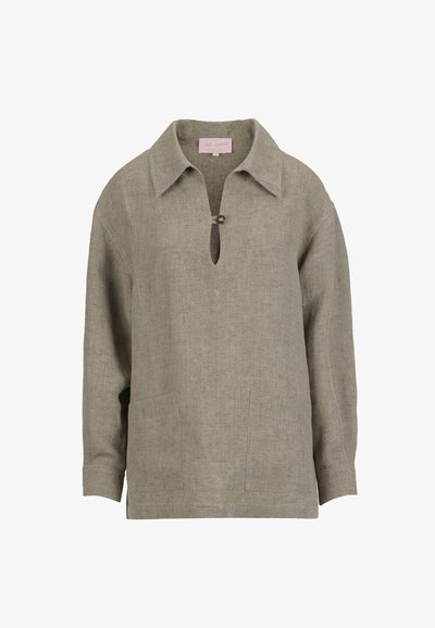 Chemise en lin beige à manches longues avec col large, fermeture à un bouton au niveau du col, et deux poches plaquées à l'avant.