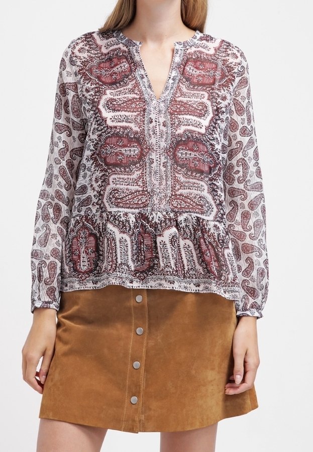 Durchsichtige Bluse mit Paisleymuster in Rot und Weiß, mit V-Ausschnitt und fließenden Ärmeln, kombiniert mit einem braunen Wildlederrock mit Knöpfen.