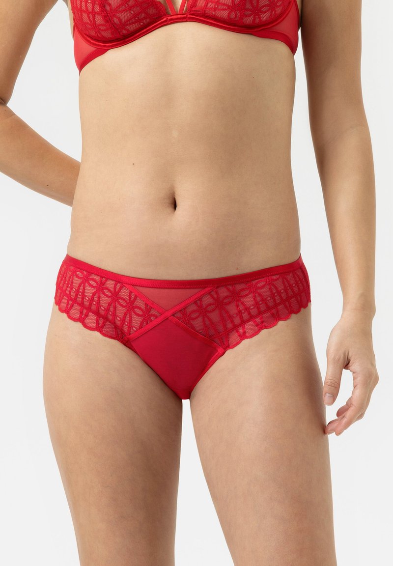 Rode lingerie in een combinatie van sheer kant en zachte stof, met gegolfde randen en geometrische patroon details aan de voorkant.