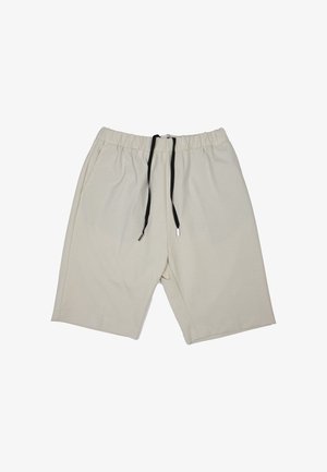 Beige shorts van zacht stof. Voorzien van een elastische tailleband met een zwarte trekkoord. Losse pasvorm met broekspijpen tot aan de knie en zonder zichtbare patronen.