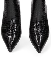 Talons aiguilles en cuir verni noir avec un motif crocodile brillant, bouts pointus et design élégant. Pas de quincaillerie ou d'accents visibles.