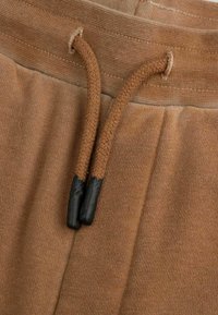 Brązowe spodnie dzianinowe z elastycznym pasem i plecionymi sznurkami z czarnymi końcówkami.