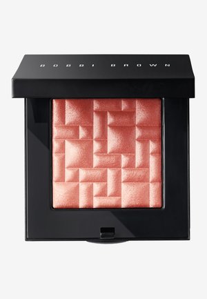 Bobbi Brown poskipunassa neliömäisessä kompaktissa; kimalteleva persikkasävy, jossa on geometrinen tekstuuri. Musta pakkaus, jossa brändin nimi päällä.