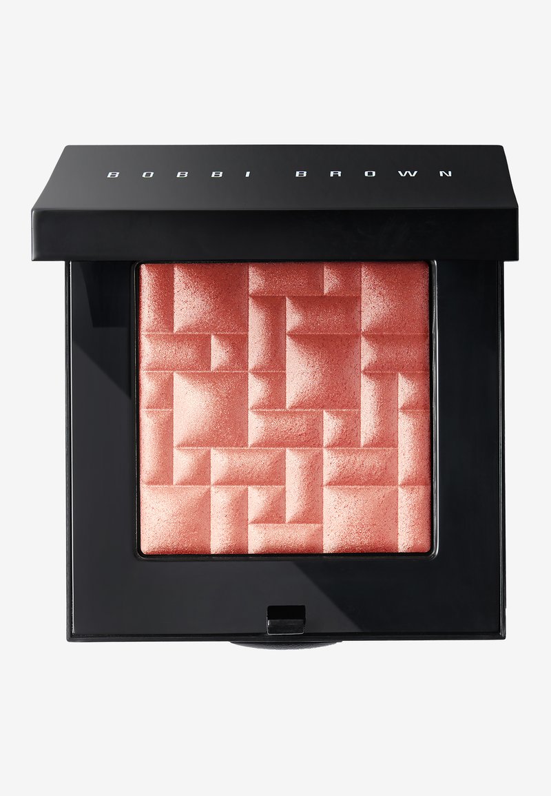 Róż Bobbi Brown w kwadratowym opakowaniu; błyszczący brzoskwiniowy odcień z geometrycznym wzorem. Czarne opakowanie z nazwą marki na górze.