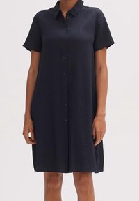 Svart kortärmad klänning med krage, knapprad framtill och texturerat tyg, med en avslappnad passform och mittlängdsdesign.