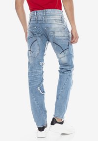 Helleblaue, distressed Jeans aus Denim mit mehreren Taschen, fransigen Kanten und kontrastierenden Nähten. Offensichtlich für eine moderne Passform entworfen.