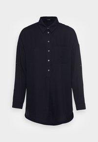 Camicia nera a maniche lunghe realizzata in tessuto leggero, con colletto, chiusura a bottoni, taschino sul petto e polsini arrotolati.