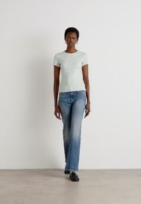 Gestreepte lichtblauwe t-shirt, gecombineerd met vervagende blauwe jeans en zwarte schoenen. Eenvoudig ontwerp, ontspannen pasvorm en gladde stoftextuur.