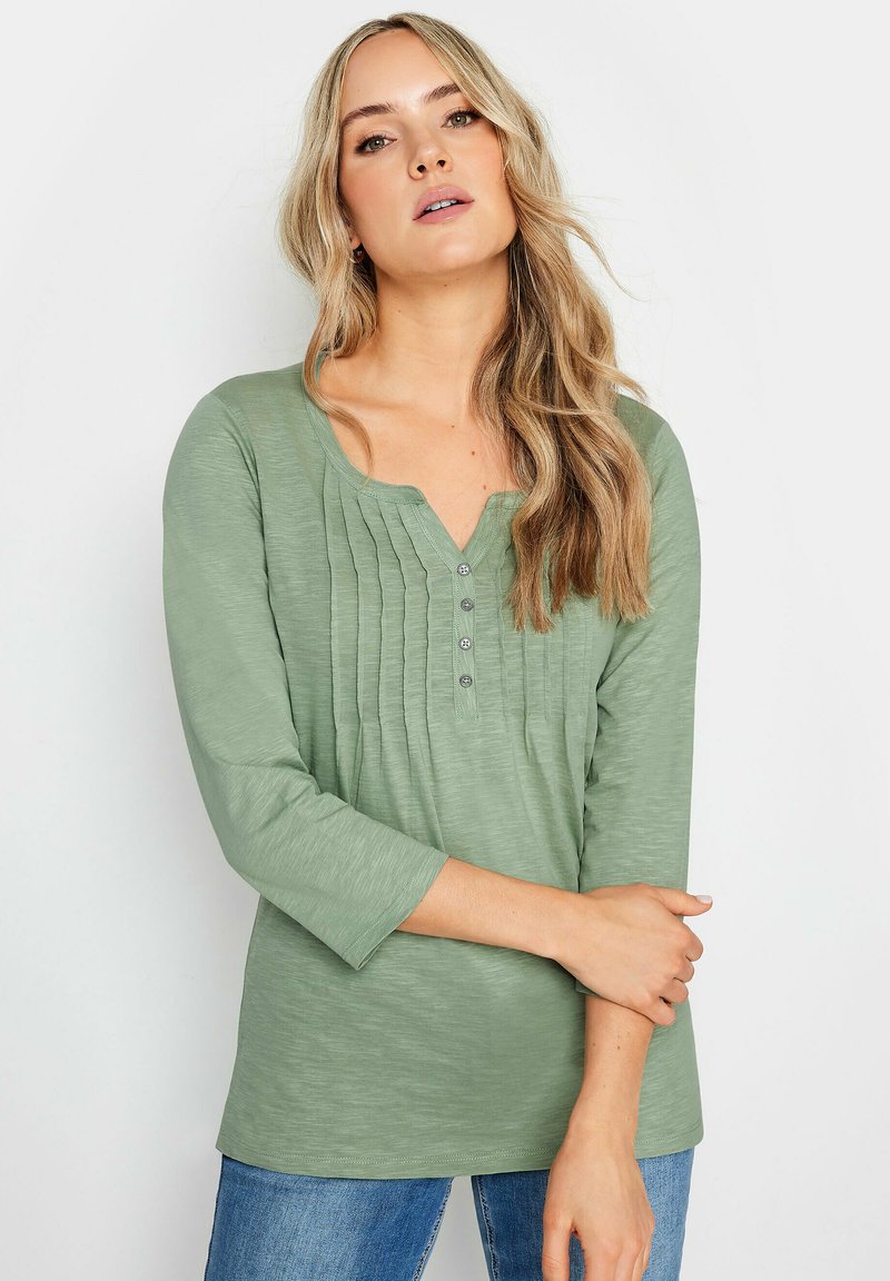 Grön långärmad tröja med V-ringning, plisserad design och knappdetaljer. Mjukt, texturerat tyg med avslappnad passform.