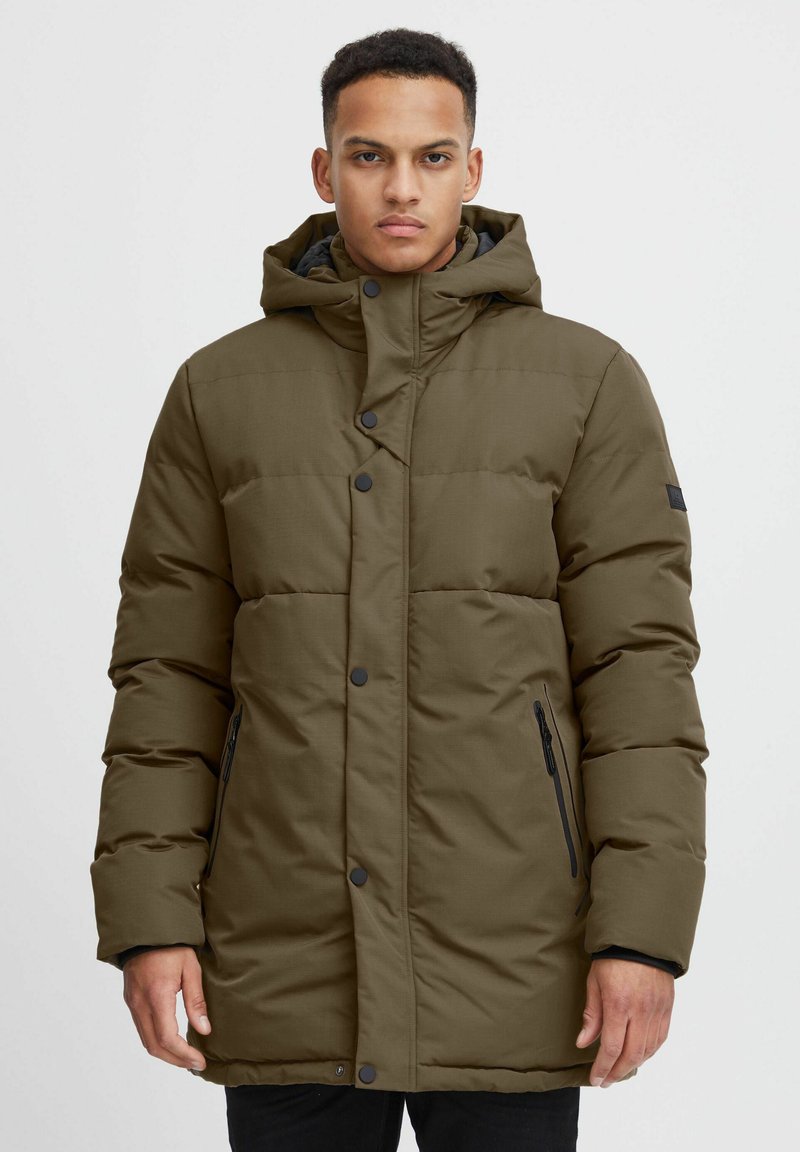 Giacca puffer verde oliva con cappuccio, dotata di bottoni a pressione, tasche laterali con cerniera e maniche allungate per un maggiore calore.