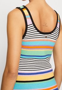 Haut débardeur tricoté multicolore avec des rayures horizontales en noir, blanc et plusieurs couleurs vives. Bretelles larges et encolure dégagée.