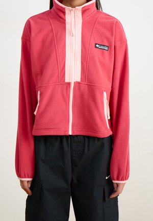 Rode Columbia fleecejas met lichtroze rits en zakafwerking, gedragen met zwarte Nike cargobroek.
