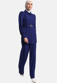 Completo due pezzi di blu royal composto da una camicia con bottoni a maniche a sbuffo e pantaloni larghi abbinati, con cintura in vita.