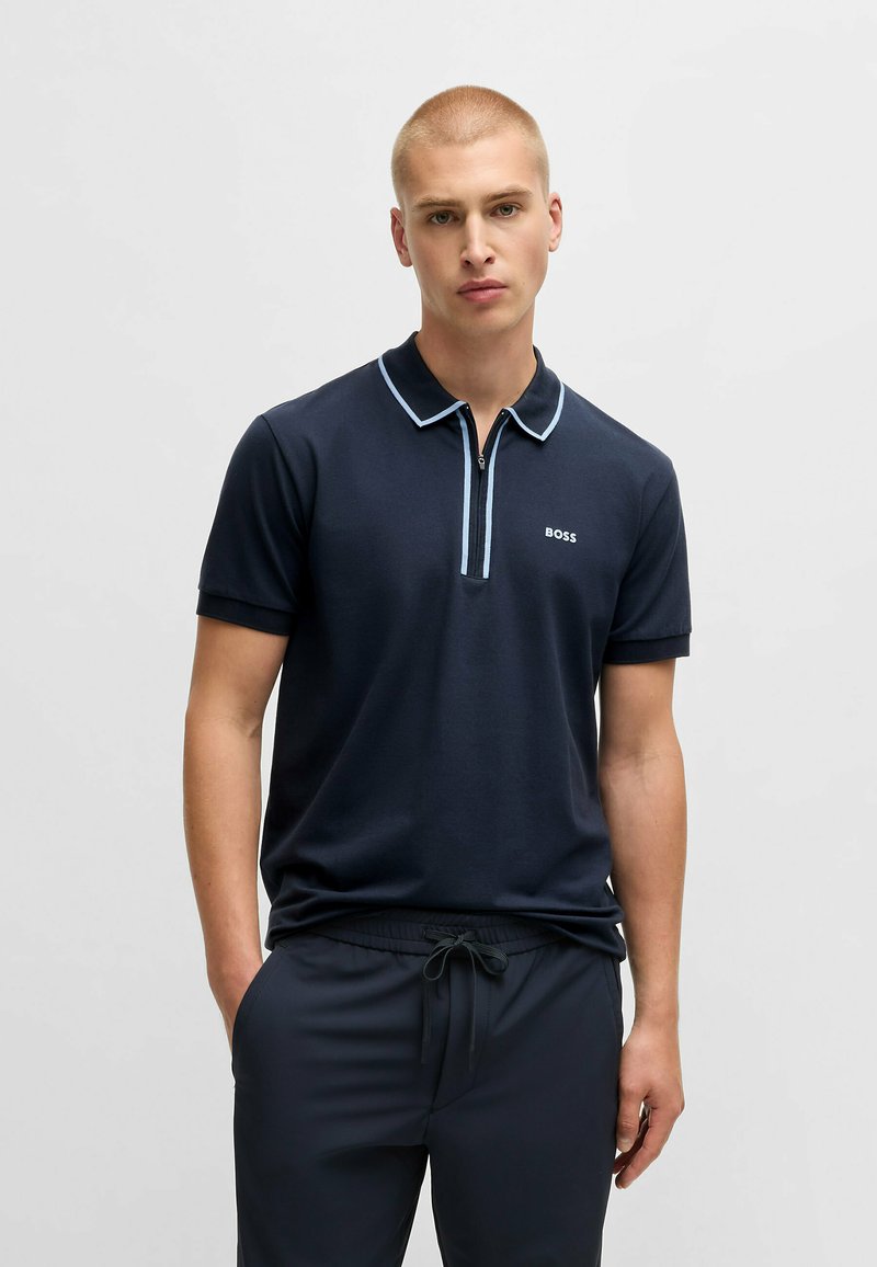 Polo shirt navy con colletto con zip, dettagli blu chiaro e logo BOSS. Tessuto morbido con maniche corte, abbinato a pantaloni scuri.