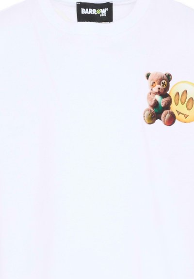 Chemise blanche avec un petit ours en peluche tenant une balle verte et un dessin d'empreinte de patte jaune avec des crocs sur la zone de la poitrine.