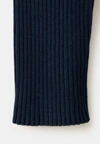 Gros plan d'un tissu tricoté côtelé bleu marine foncé avec des lignes texturées verticales et un bord légèrement courbé en bas.
