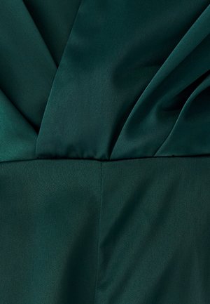 Dunkelgrüner Satinstoff mit glatter Textur, der überlappende Falten und einen subtilen Glanz aufweist, was ein strukturiertes und elegantes Erscheinungsbild schafft.
