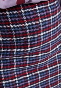 Rutiga kjolen med blandade färger: röd, lila, blå och vit. Tyget har en ullig textur med en figurnära passform och en midilängd.