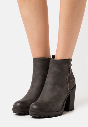 Bottes noires jusqu'à la cheville avec une finition texturée, fermeture éclair latérale et talon haut épais. Dotées d'une semelle en caoutchouc cloutée pour une meilleure adhérence.