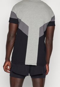 Kortärmad t-shirt med en färgblockdesign i grått, svart och mörkgrått. Tyget verkar mjukt med en avslappnad passform.