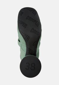 Grön textilskor med gummisula, med präglad "CAMPER"-logotyp, rund häl och storlek 38 markerad på sulan.