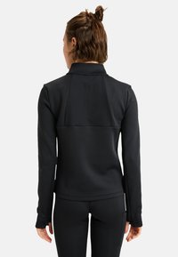 Zwarte longsleeve top met een opstaande kraag, textuurstof en duimgaten bij de mouwen, gecombineerd met bijpassende aansluitende broek.