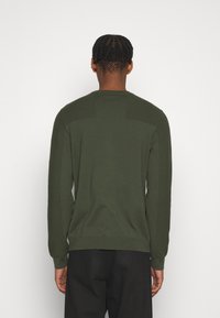 Grüner Strickpullover mit langen Ärmeln, geripptem Muster an Schultern und Bündchen, mit Rundhalsausschnitt und tailliertem Saum.