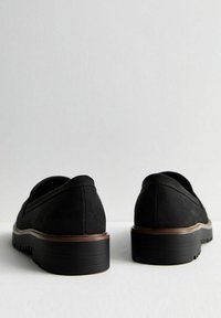 Black suede shoes with a rounded toe, flat sole, and brown accents on the heel. Textured surface and low-cut design for comfort.
