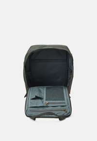 Sac à dos en tissu vert avec un intérieur spacieux bleu clair doté de plusieurs poches et d'un compartiment zippé pour un rangement organisé.