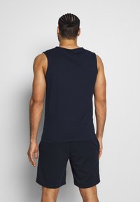 Top senza maniche blu navy realizzato in cotone, presenta un collo rotondo, una superficie liscia ed è abbinato a pantaloni sportivi coordinati.