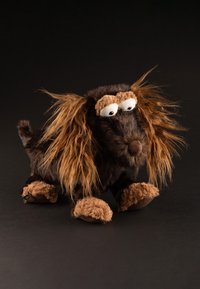 Plush toy dog with black fur and long, light brown faux fur accents. Large white eyes, a brown nose, and soft tan paws complete the design.