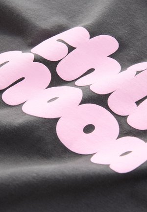 Tela gris con letras rosas grandes y audaces de bordes redondeados, que muestra una textura suave y un ligero brillo.