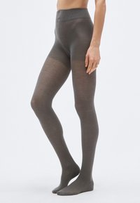 Graue gemusterte Strumpfhosen mit Fischgrätmuster, ausgestattet mit einem hohen Bund und einer glatten Oberfläche. Die Füße sind barfuß.