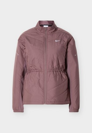 Veste zippée pour femme couleur mauve clair avec col montant, taille et poignets élastiques, et logo Nike swoosh blanc sur la poitrine.