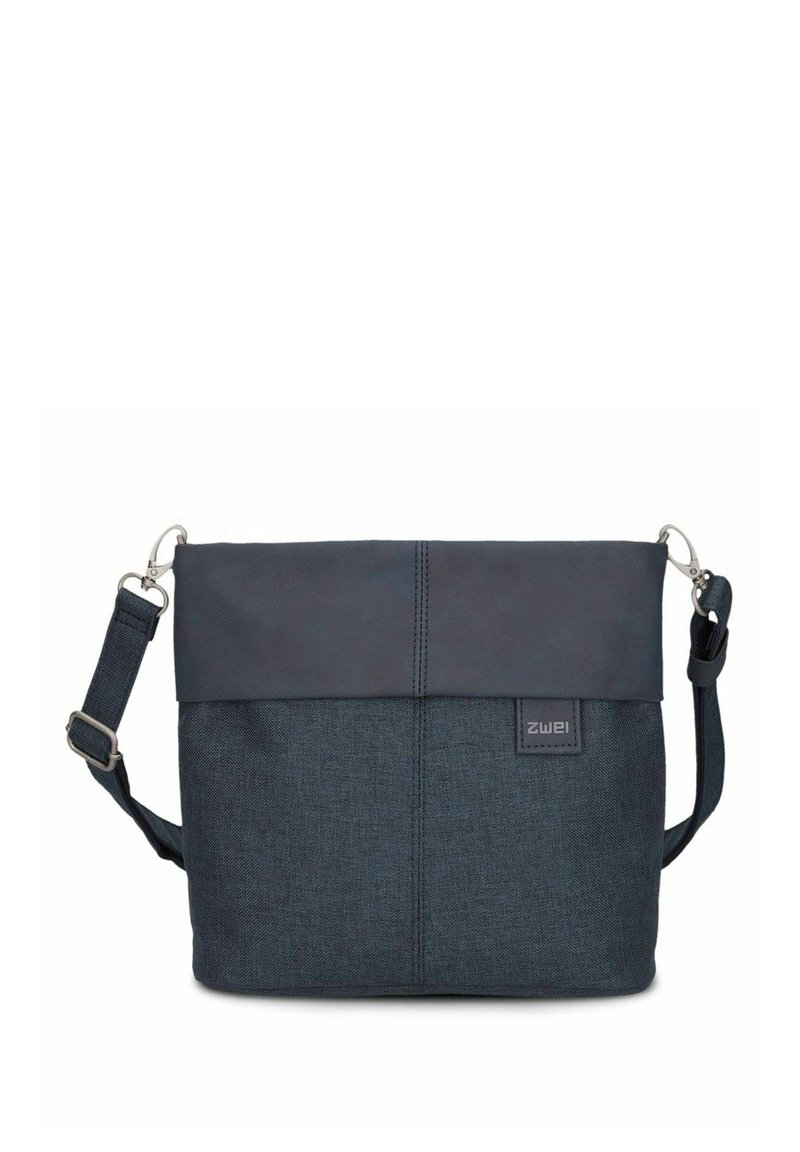 Bolso azul oscuro con una tela texturizada y parte superior de cuero suave. Presenta una correa ajustable y una etiqueta con el logo en el frente. Forma rectangular estándar.