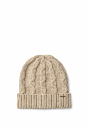 Femme souriante portant un bonnet tricoté beige et des gants à motif torsadé ainsi qu'une doudoune noire avec un logo brodé.