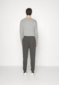 Grijze longsleeve top, gecombineerd met donkergrijze joggings met een achterzak. Eenvoudig ontwerp met ribgebreide manchetten en witte sneakers.