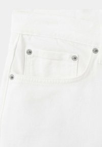 Gros plan d'une poche de jean en denim blanc avec des coutures visibles et quatre rivets argentés aux coins pour le renfort.